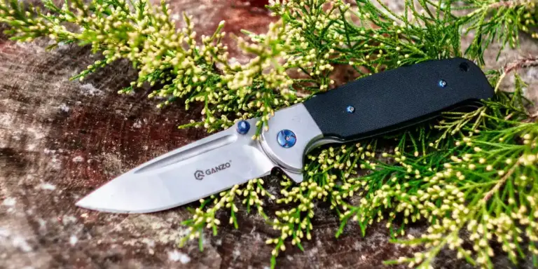A folding knife resting on green plant foliage, creating a tense, symbolic contrast.