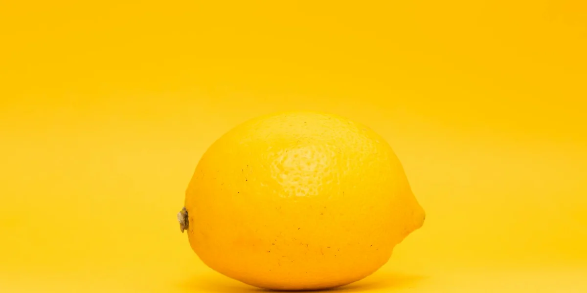 A bright yellow lemon placed on a yellow background