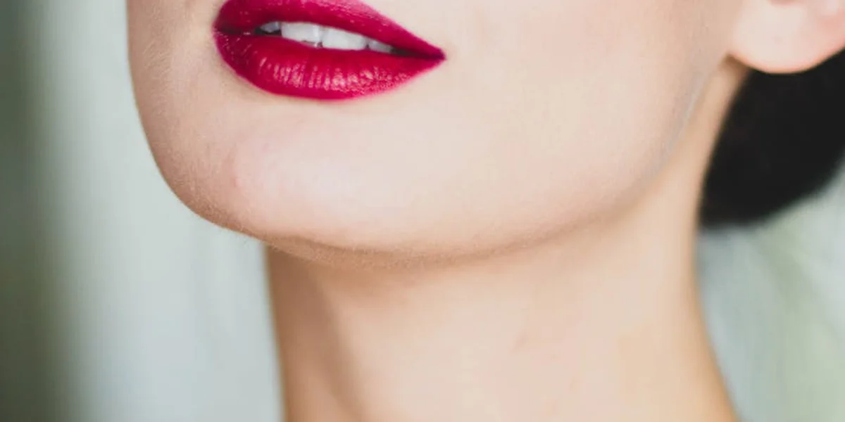 Close-up of a woman's lips with bright red lipstick; eyes are not visible.