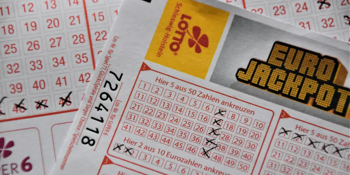 Close-up of lottery tickets and a numeric grid with Lotto and Euro Jackpot headlines visible.