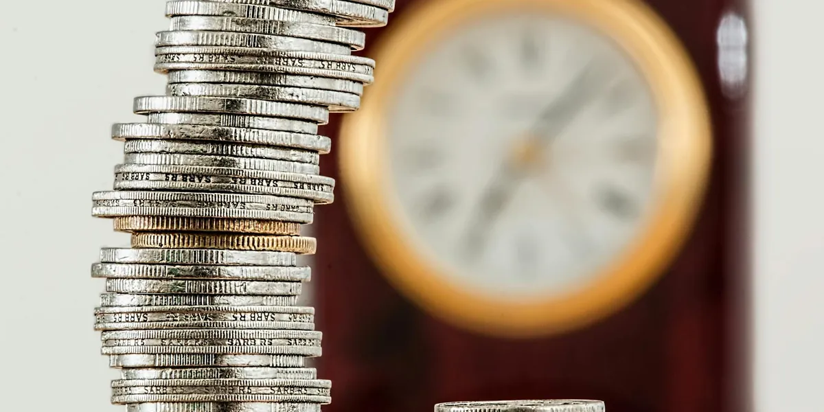 A tall stack of coins beside a blurred clock, symbolizing money, time, and the need to interpret dream imagery.