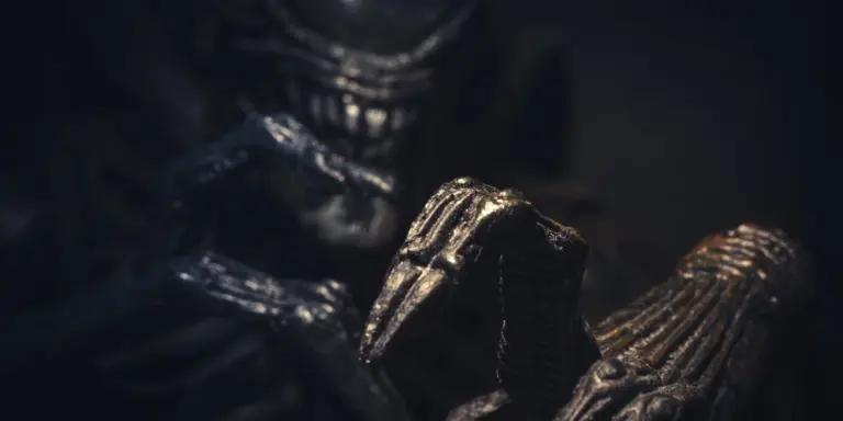 Dark, close-up image of a menacing, demon-like clawed figure obscured by shadows