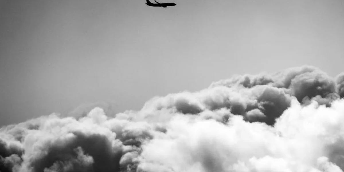Black-and-white image of a small airplane flying above fluffy clouds, symbolizing a turning point in spiritual awakening.