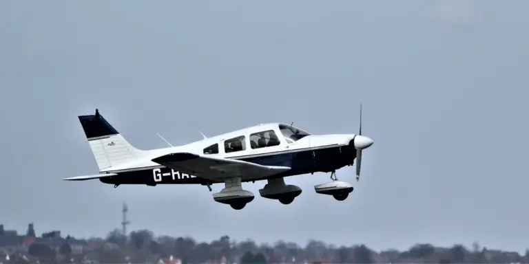 Small single-engine propeller plane flying over a rural landscape