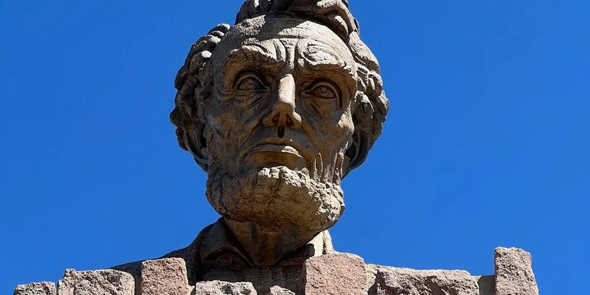 Close-up of a stone bust of a bearded president against a clear blue sky