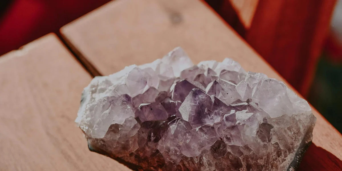 A cluster of purple amethyst crystals resting on a warm wooden surface.