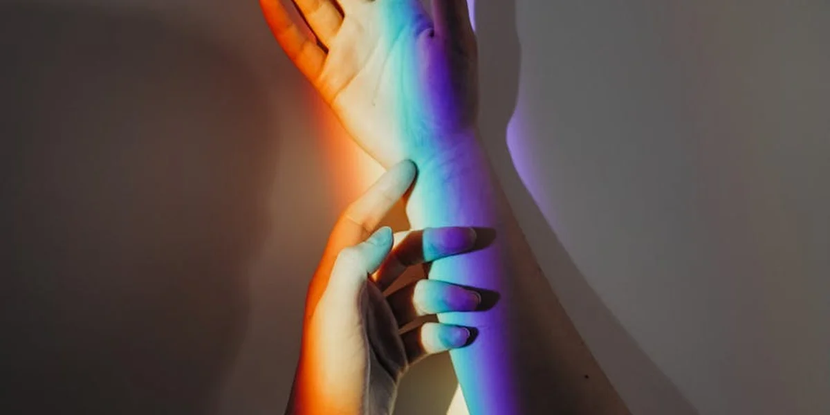 Hands bathed in multicolored rainbow light, symbolizing diverse spiritual meanings