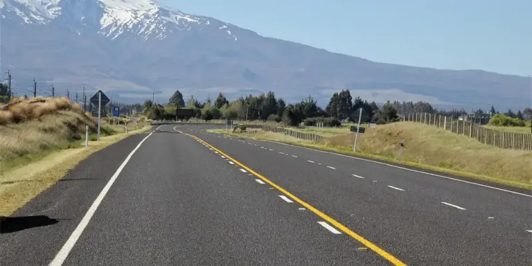 Long, empty rural road stretching toward distant mountains under a clear blue sky, symbolizing freedom and new beginnings in retirement.
