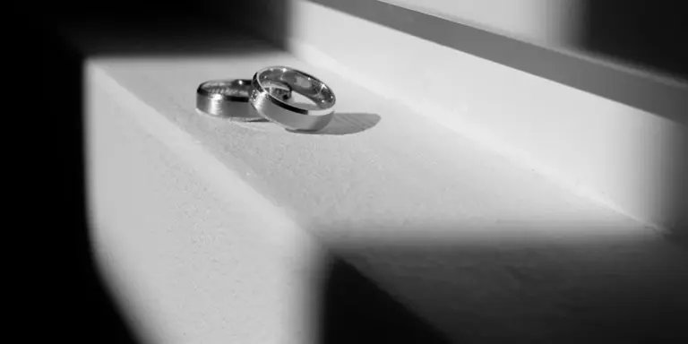 Two wedding rings resting on a white surface in grayscale, symbolizing separation and spiritual change.
