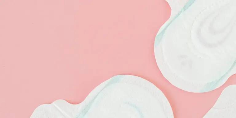 Close-up of sanitary pads on a pink background, representing menstruation and feminine care.