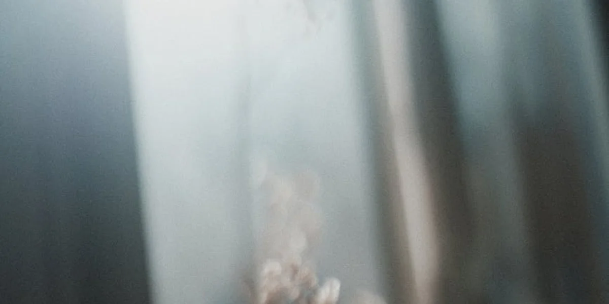 Abstract, blurred image of reflective glass with cool blue-gray tones, suggesting mystery and coded messages from the subconscious.