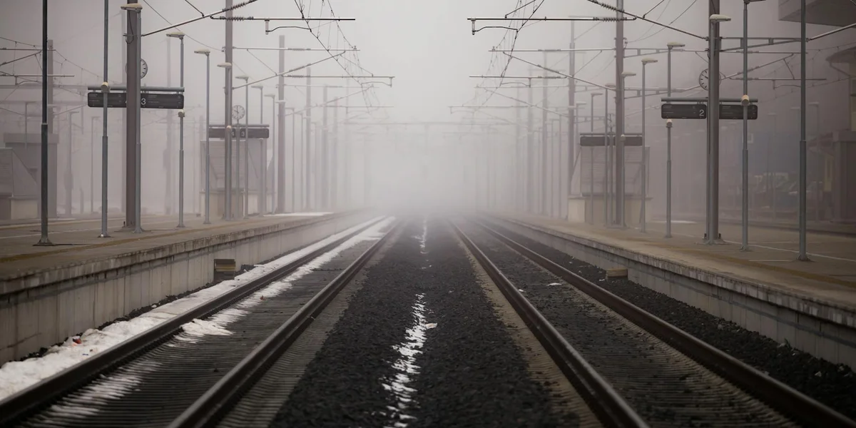 Foggy train station with rails receding into the mist