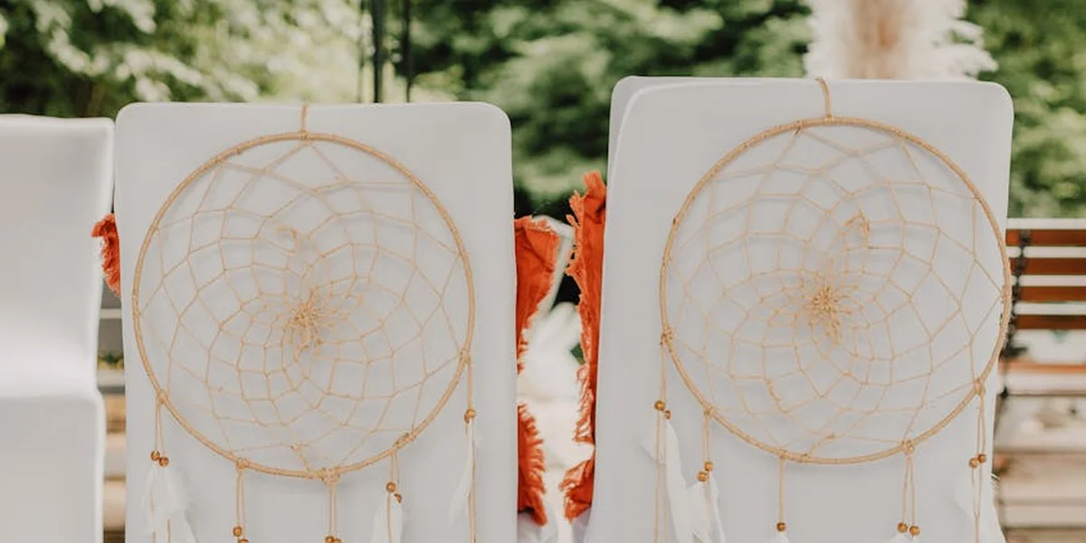 Two circular dreamcatchers hanging outdoors between white panels