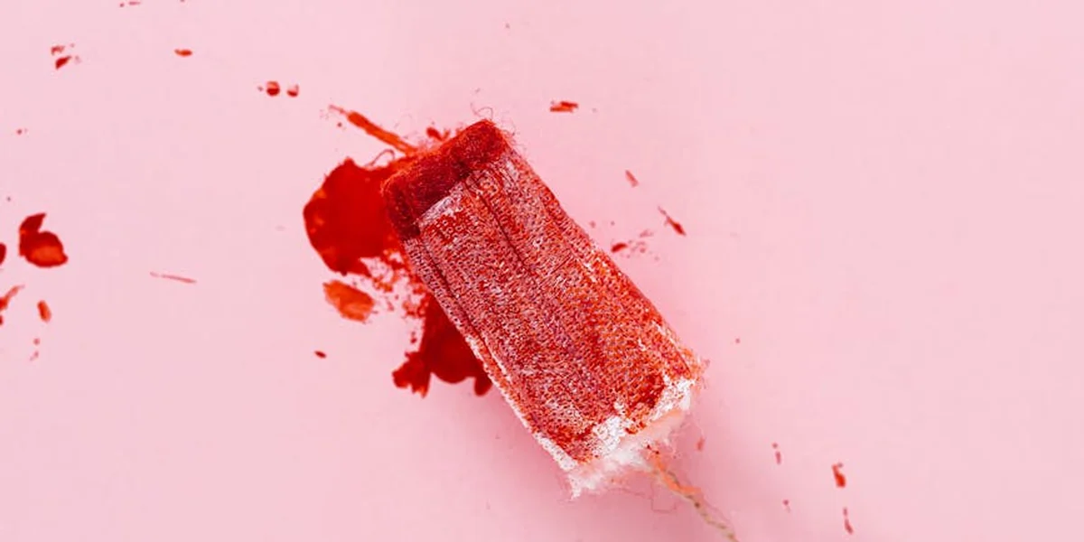 Close-up of a pink background with a red, blood-stained rectangular object, symbolizing bleeding in dreams.
